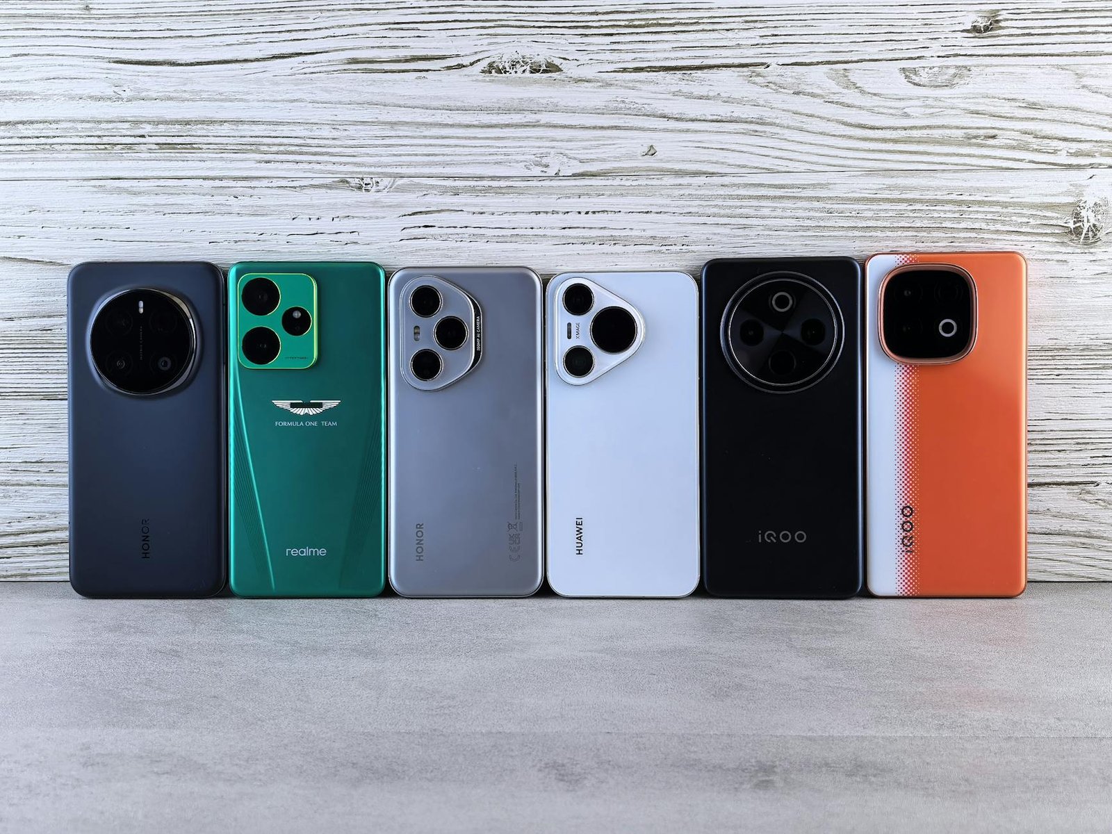 Array of modern smartphones displayed against a wooden texture, showcasing different designs and colors.