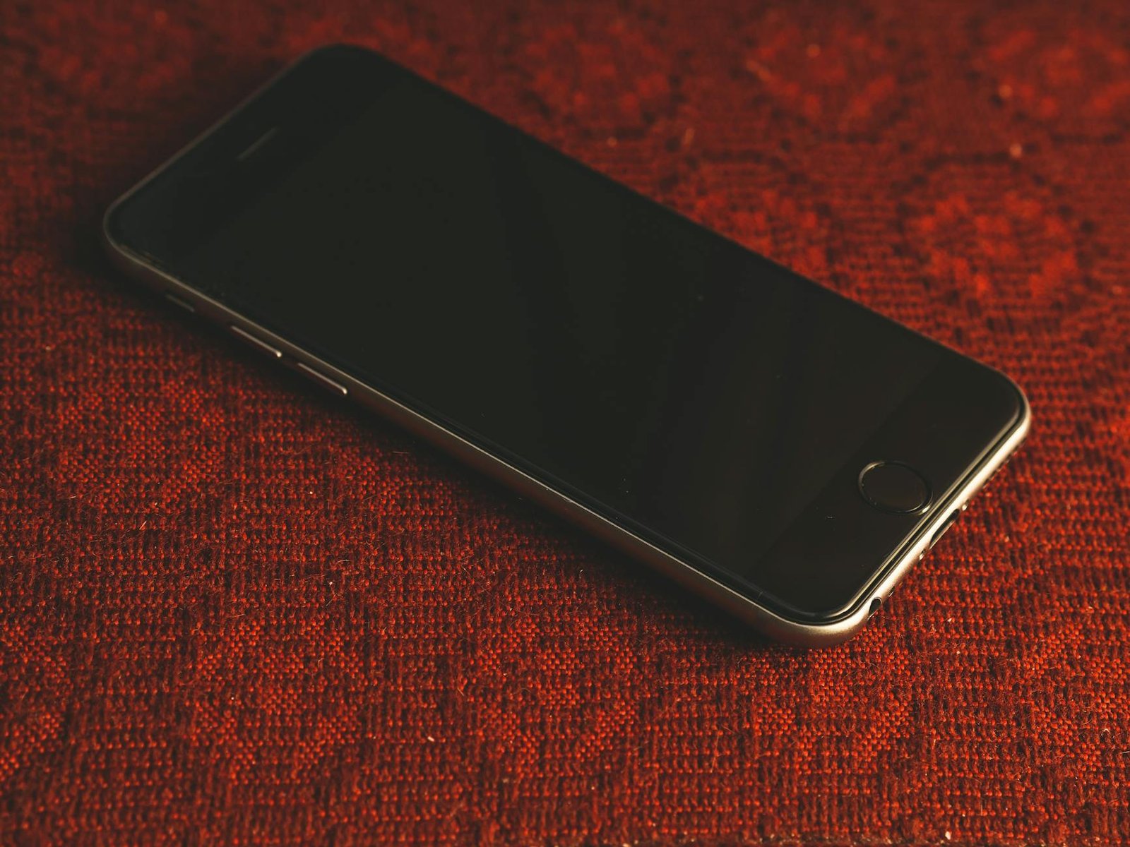 A smartphone resting on a textured red fabric surface, showcasing modern technology and design.