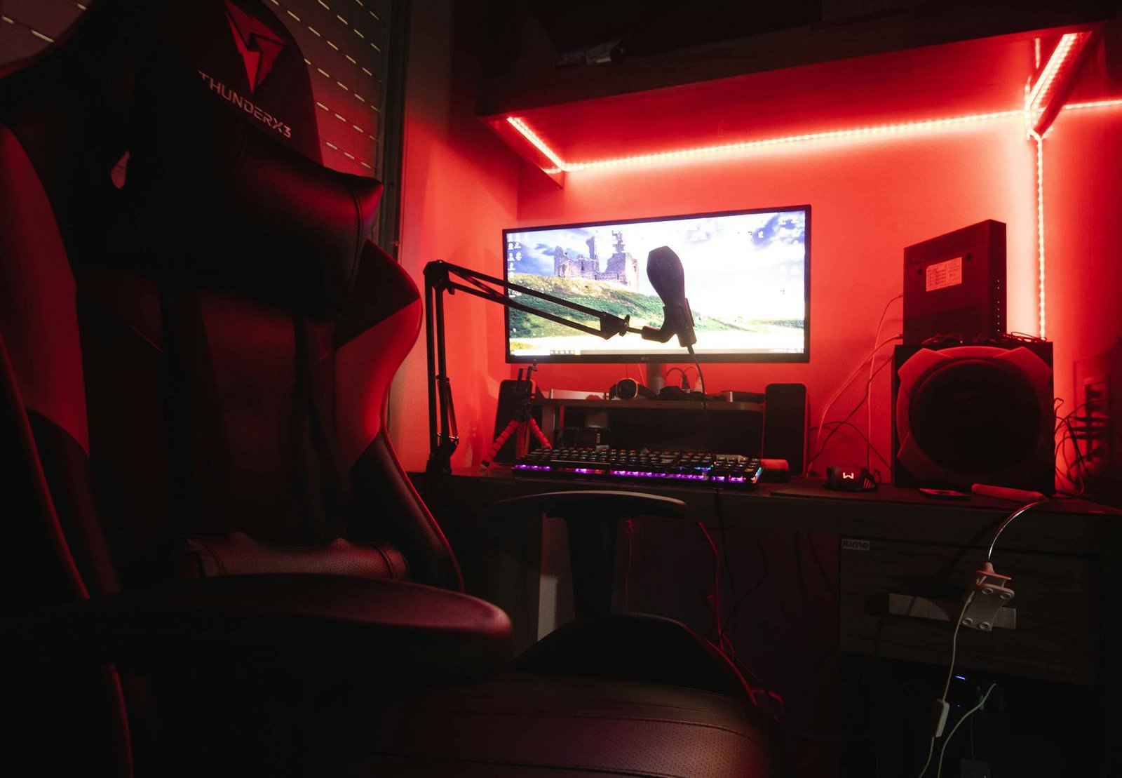Sleek gaming setup featuring a microphone, neon lights, and a gaming chair in a home studio.
