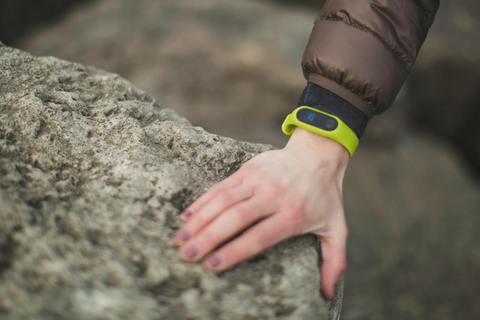 Close-up of a hand with a fitness tracker touching a rock outdoors, showcasing exploration.