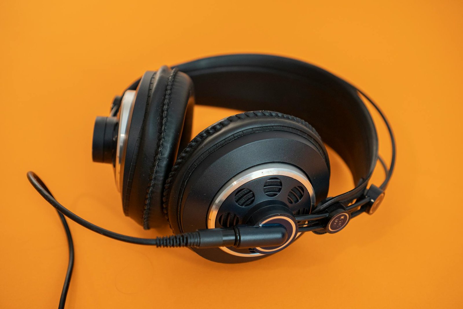 Close-up of professional headphones on a vivid orange background, ideal for audio and tech concepts.