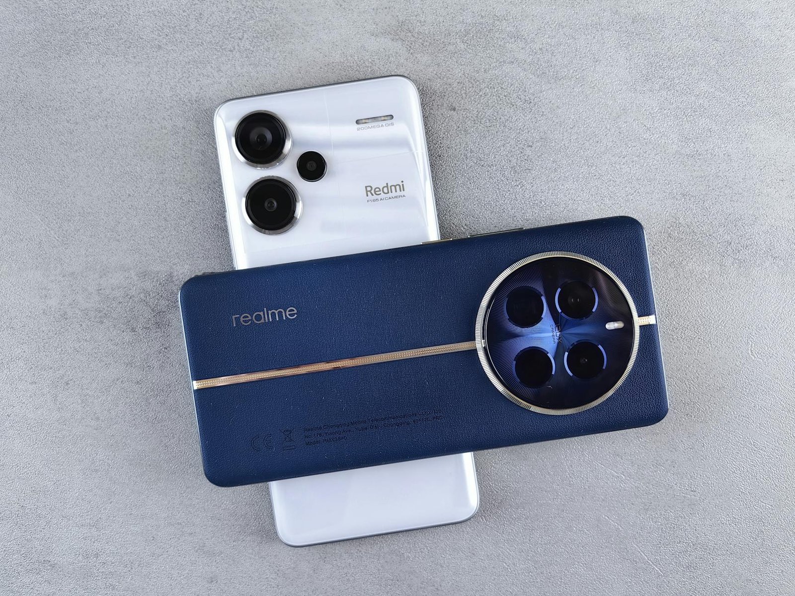 Flat lay of two modern smartphones with prominent camera designs on a concrete surface.