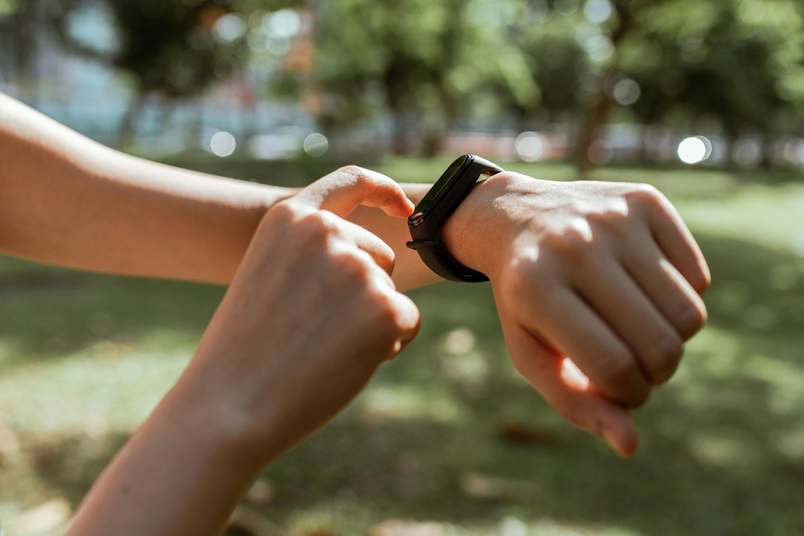 A person interacts with a smartwatch in a sunny park, emphasizing fitness and technology.