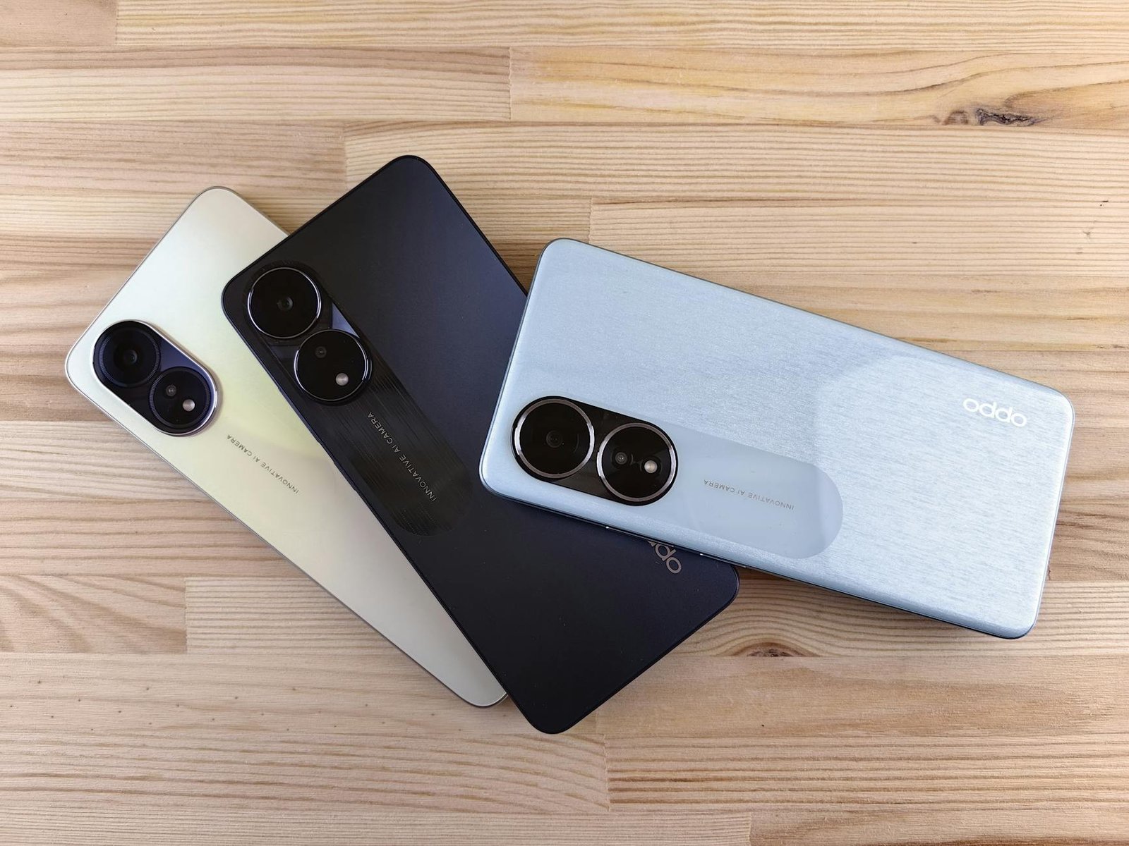 Three modern smartphones displayed on a wooden surface, showcasing design and color variants.