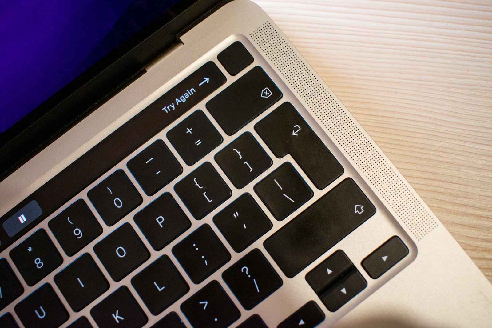 High-resolution close-up of a modern laptop keyboard positioned on a light wooden table, capturing details.