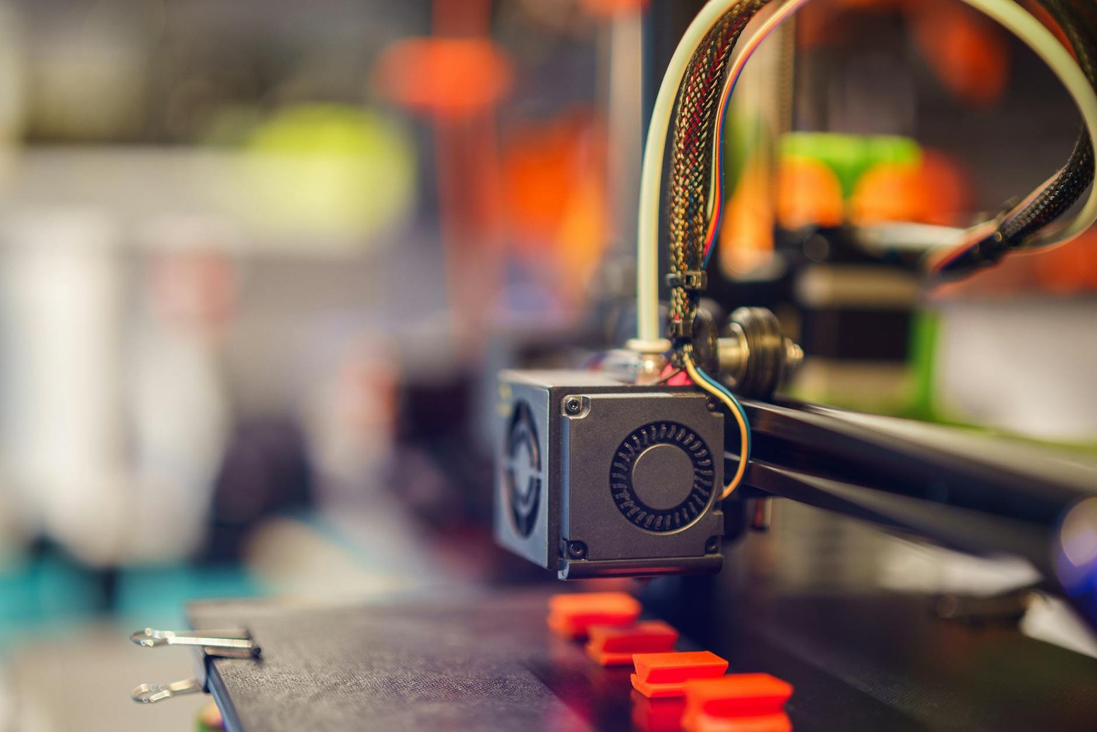 Detailed close-up of a 3D printer extruding red plastic during operation.