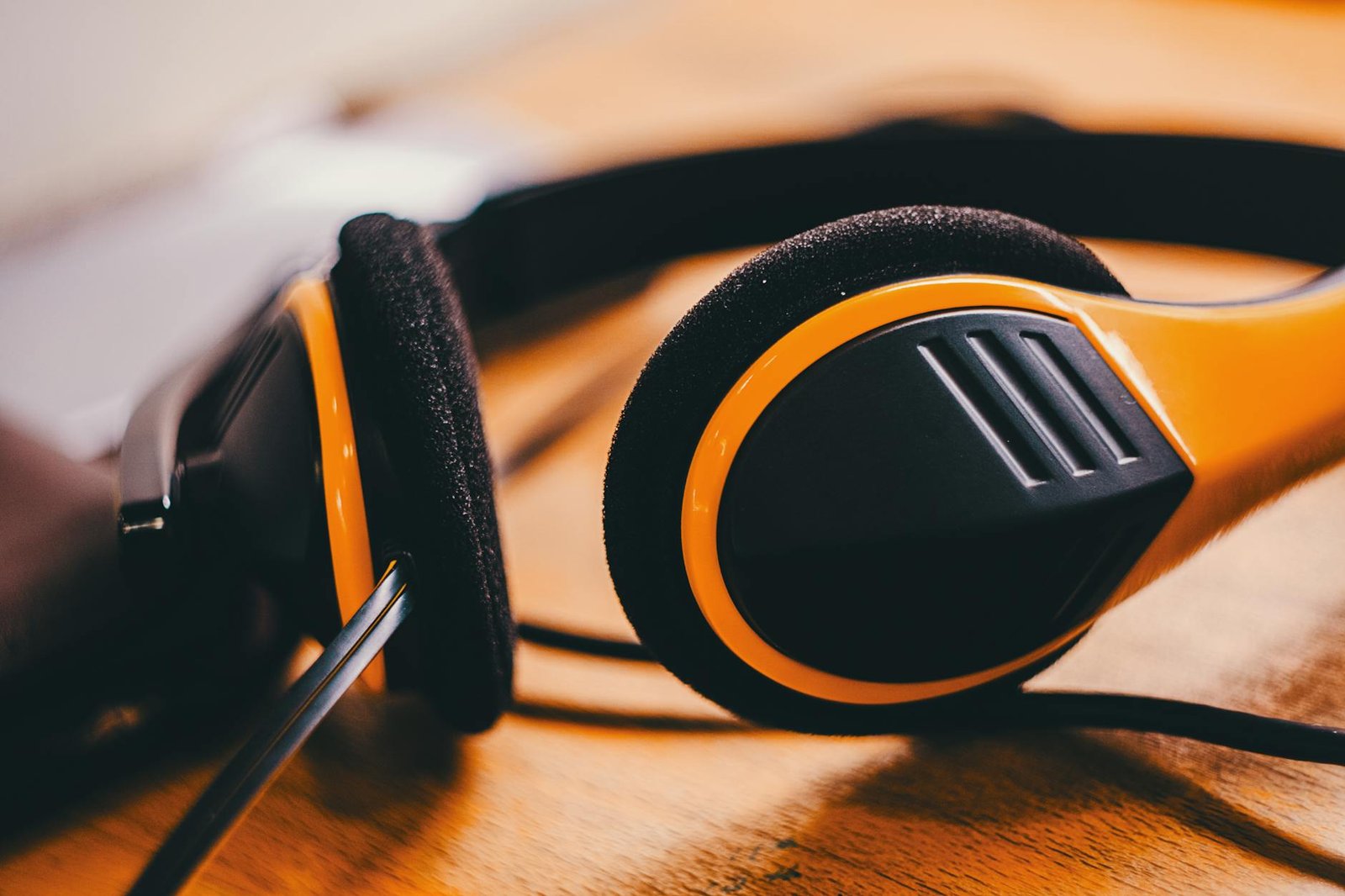 Detailed close-up of yellow and black headphones lying on a wooden surface, showcasing modern design.