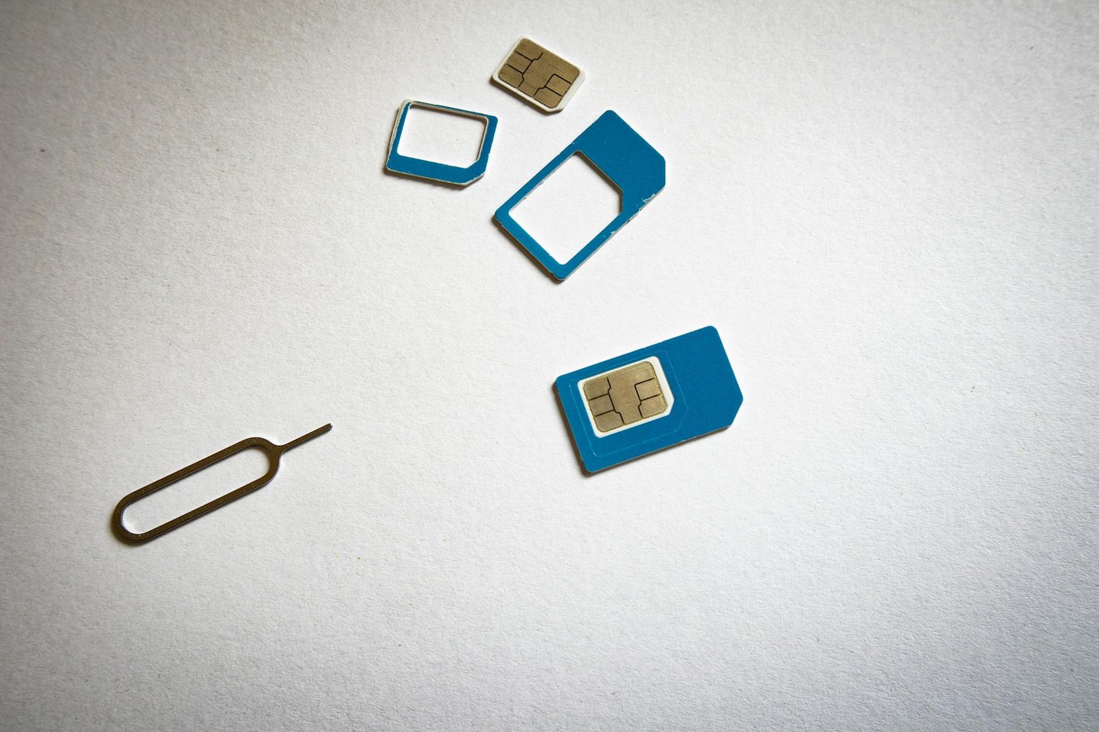 Close-up of SIM cards and ejector tool on white background, emphasizing telecommunication technology.