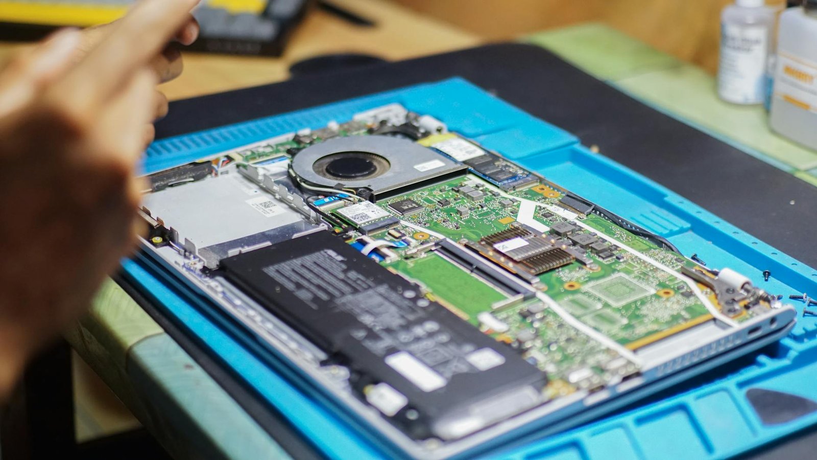 Close-up of laptop being repaired with visible components and tools.