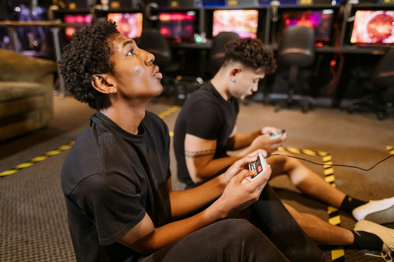 Two teenagers deeply engaged in a video gaming session at an indoor arcade.