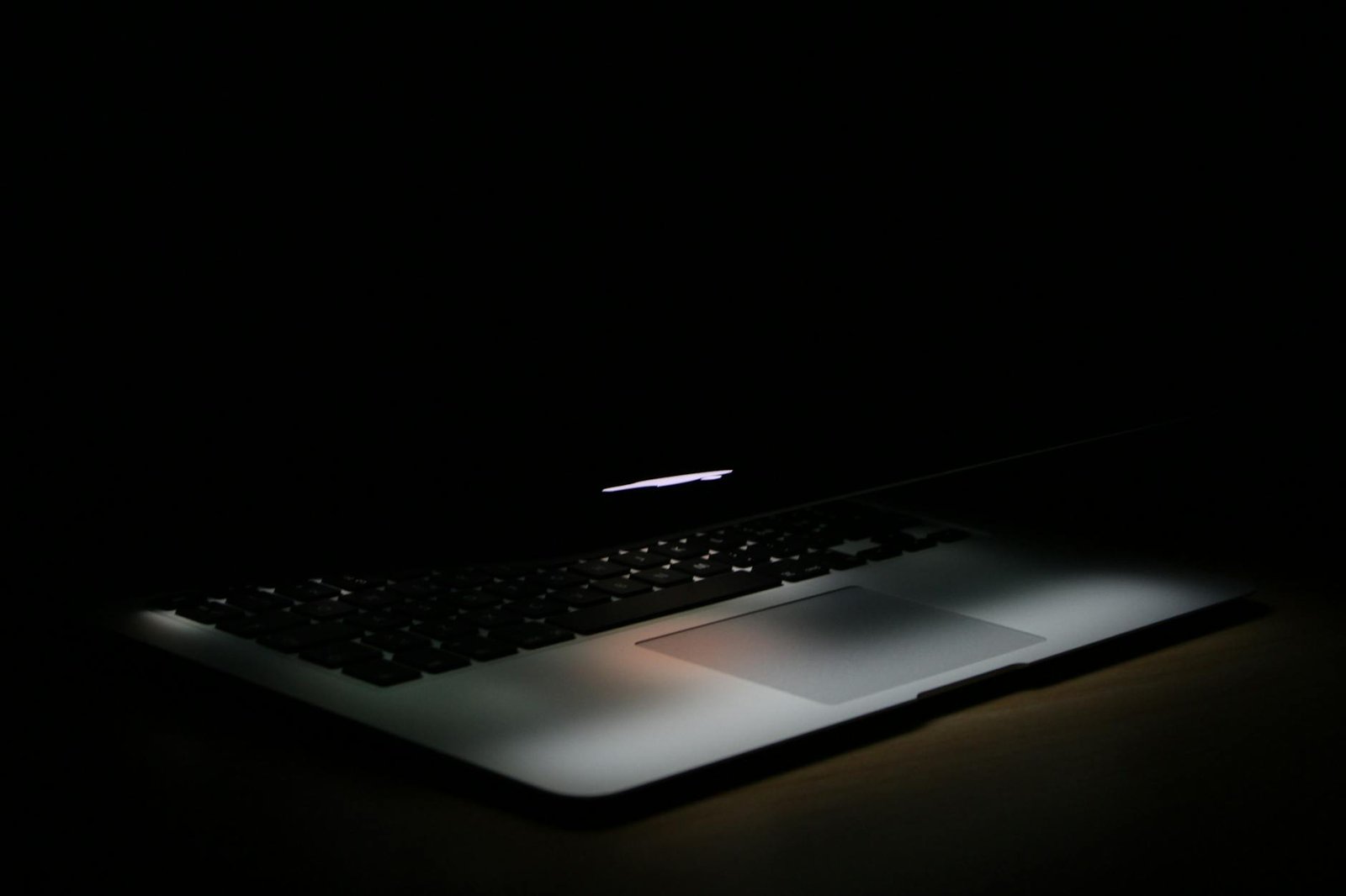 A sleek laptop with soft backlighting in a dark, minimalist setting.