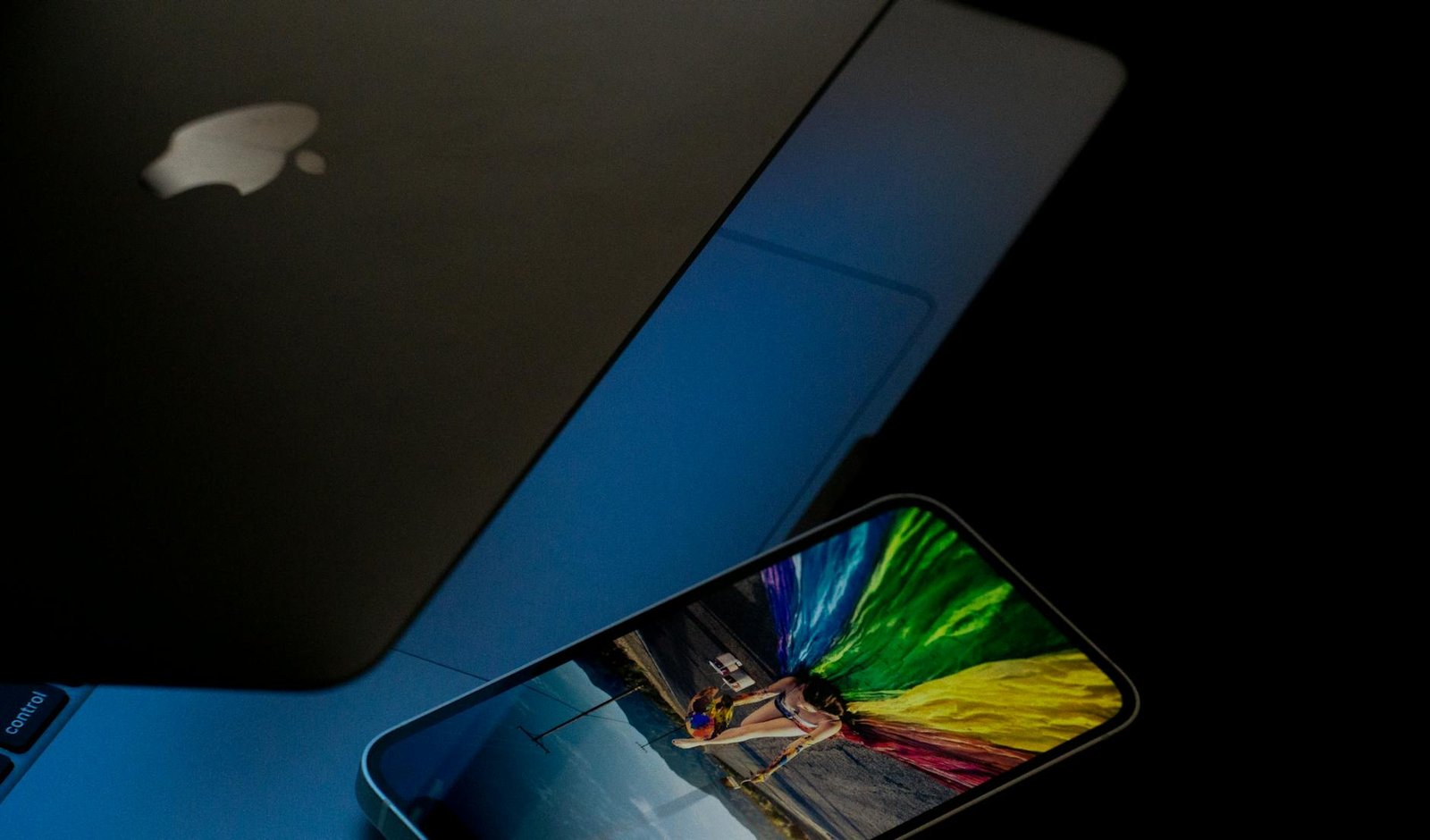 A vibrant smartphone screen displaying colorful imagery next to a laptop in low light.