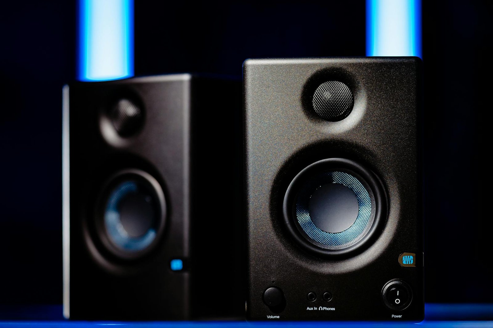 Close-up of modern black loudspeakers with blue accents in a studio setting.