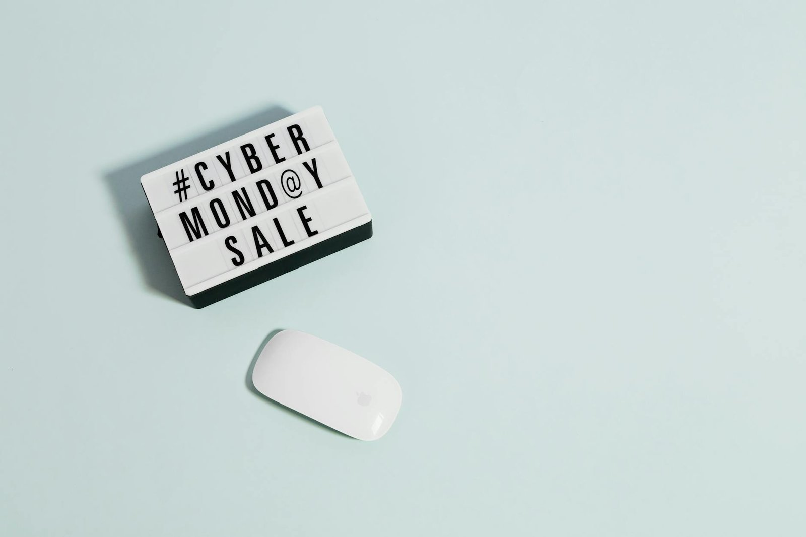 Minimalist design depicting Cyber Monday sale concept with a white mouse on pastel background.
