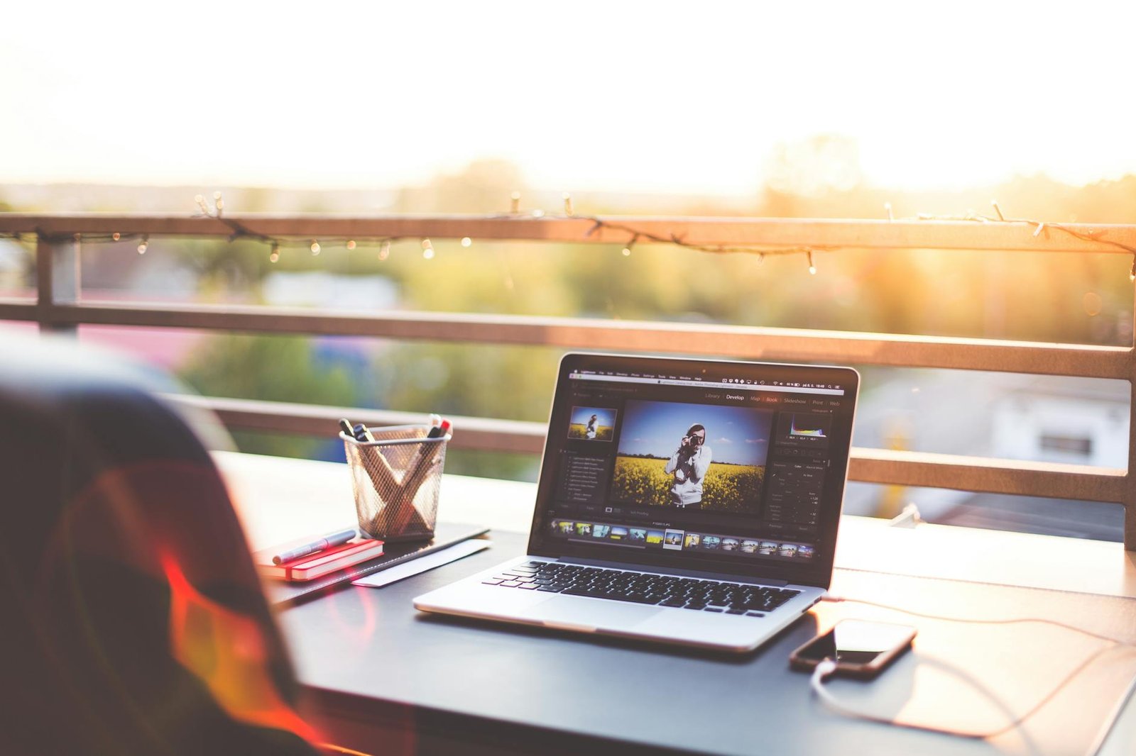 A modern workspace on a balcony with a laptop and smartphone during sunset, capturing a creative work environment.