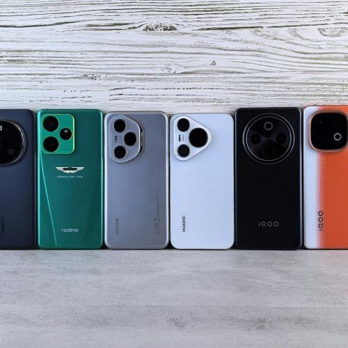 Array of modern smartphones displayed against a wooden texture, showcasing different designs and colors.