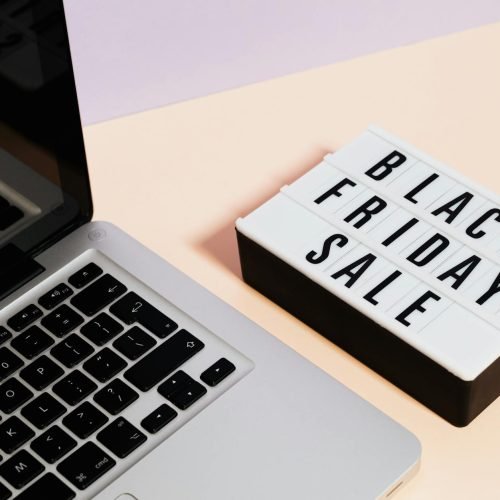 A laptop beside a lightbox sign with 'Black Friday Sale' for online shopping promotions.