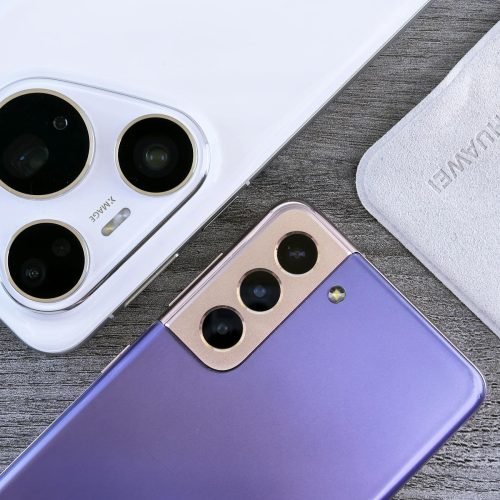 Close-up of two smartphones with camera focus on a textured wooden surface.