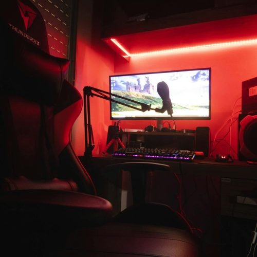 Sleek gaming setup featuring a microphone, neon lights, and a gaming chair in a home studio.