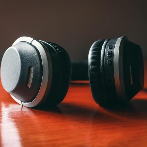 Close-up of wireless headphones on a wooden table, emphasizing design and technology.