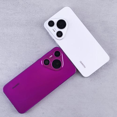 Two Huawei smartphones, one white and one purple, on a textured concrete surface.