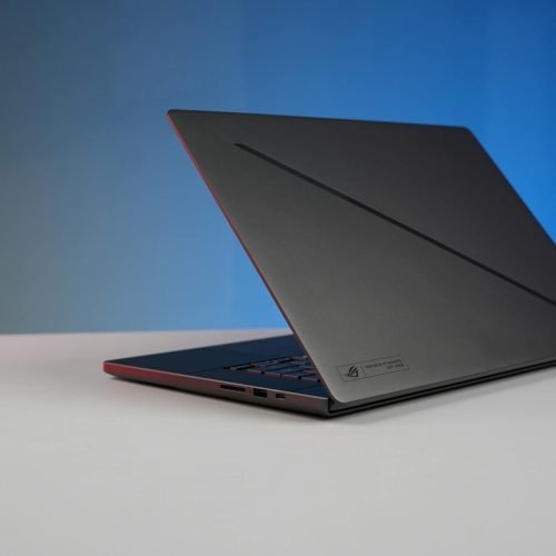 Elegant black laptop on a minimalist desk with a gradient blue background, perfect for tech and work concepts.