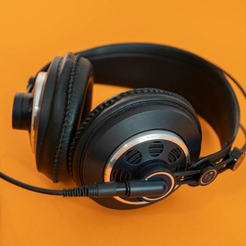 Close-up of professional headphones on a vivid orange background, ideal for audio and tech concepts.