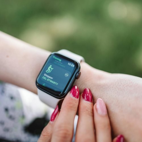 Woman interacting with a smartwatch outdoors displaying a fitness tracking app.