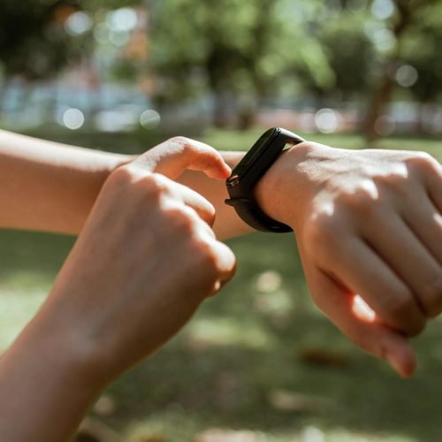 A person interacts with a smartwatch in a sunny park, emphasizing fitness and technology.