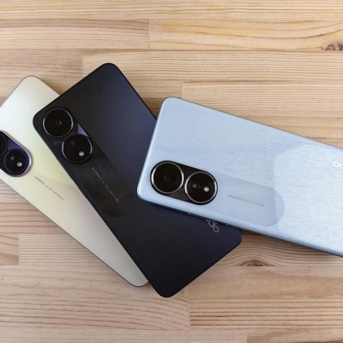 Three modern smartphones displayed on a wooden surface, showcasing design and color variants.