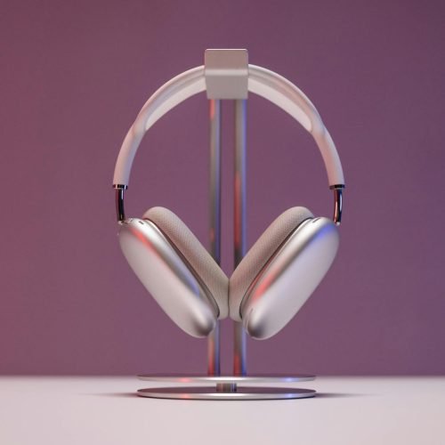 Stylish over-ear headphones displayed on a stand against a pink backdrop.
