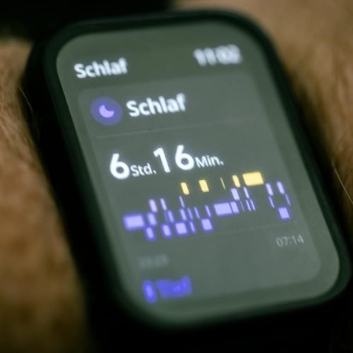 Close-up of a smartwatch displaying sleep tracking data in German.