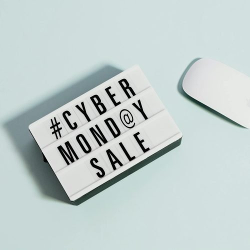 Lightbox sign displaying 'Cyber Monday Sale' beside a computer mouse on a pastel background.