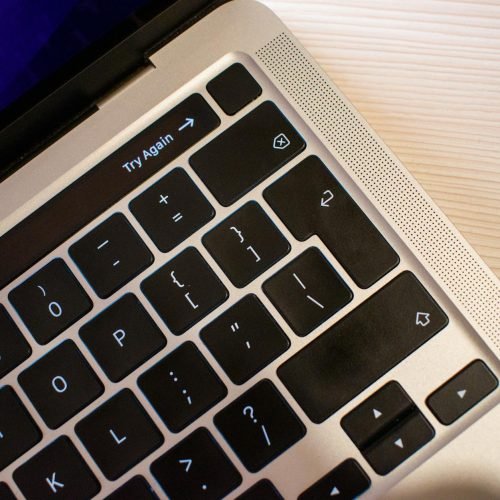 High-resolution close-up of a modern laptop keyboard positioned on a light wooden table, capturing details.