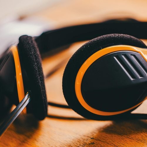 Detailed close-up of yellow and black headphones lying on a wooden surface, showcasing modern design.