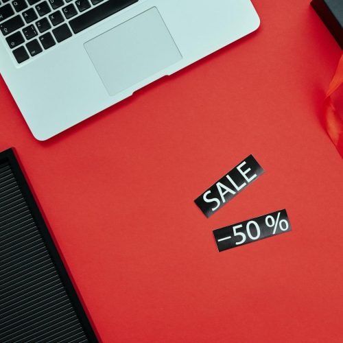 Overhead view of a laptop and gift box on a red surface with Black Friday sale sign.