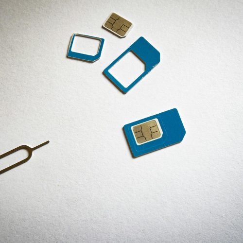 Close-up of SIM cards and ejector tool on white background, emphasizing telecommunication technology.