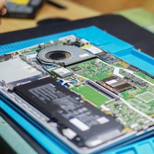 Close-up of laptop being repaired with visible components and tools.