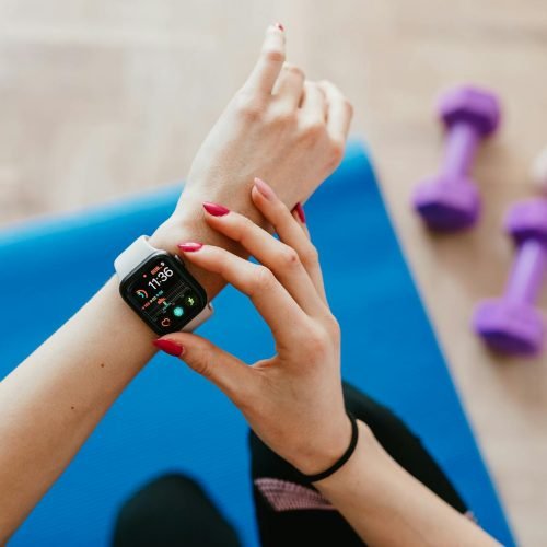 A woman checks fitness data on her smartwatch during a workout at home.