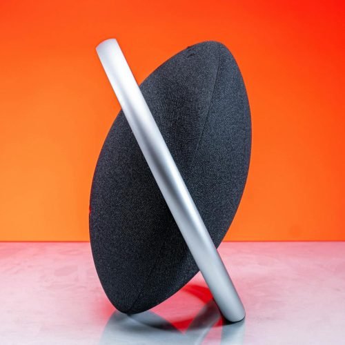 Contemporary wireless speaker set against a vivid orange backdrop, showcasing sleek design.