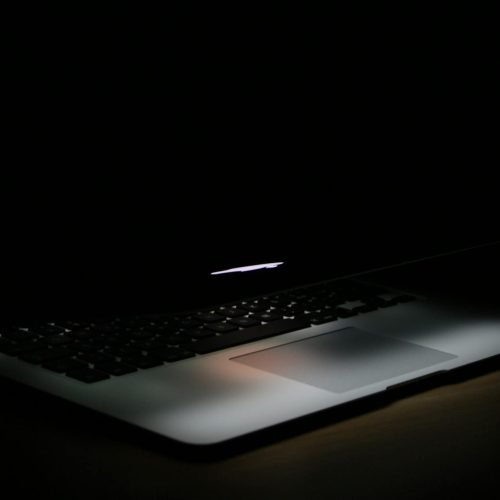 A sleek laptop with soft backlighting in a dark, minimalist setting.