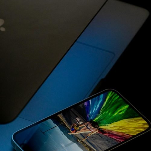 A vibrant smartphone screen displaying colorful imagery next to a laptop in low light.