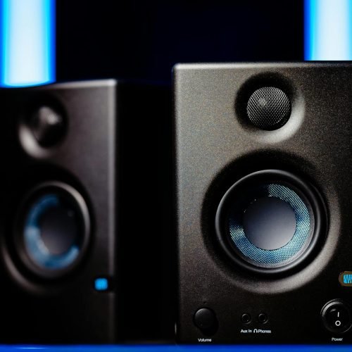 Close-up of modern black loudspeakers with blue accents in a studio setting.