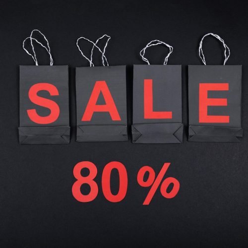 Highlighting a sale with 80% discount using black shopping bags and bold red text.