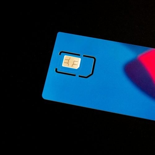 A blue SIM card on a dark background with vibrant red and purple accents.