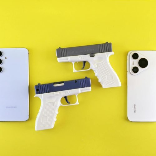 Flat lay of white smartphones and toy guns on a vibrant yellow backdrop, modern concept.