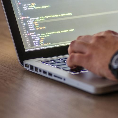 A close-up shot of a person coding on a laptop, focusing on the hands and screen.