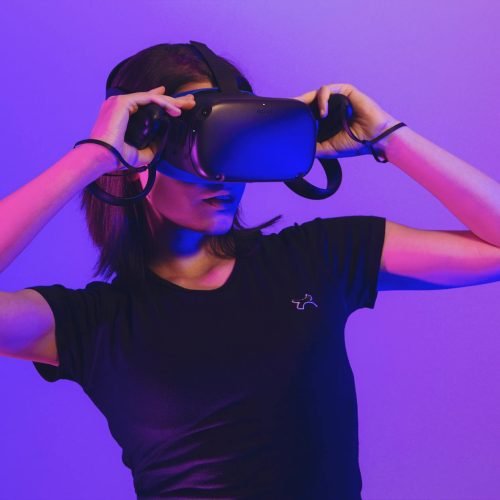 Woman wearing virtual reality headset immersed in a vibrant neon-lit gaming experience.