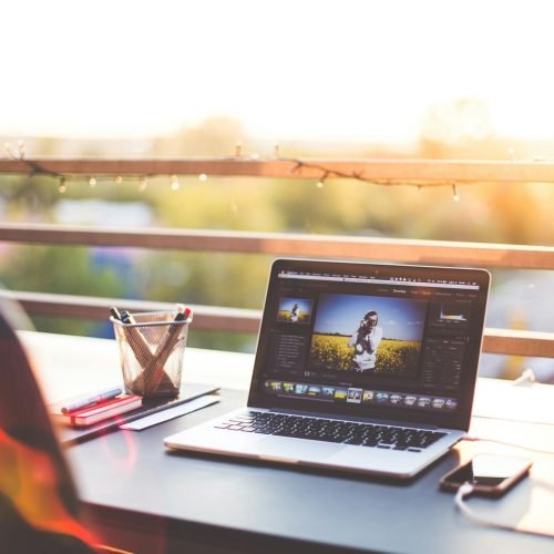 A modern workspace on a balcony with a laptop and smartphone during sunset, capturing a creative work environment.